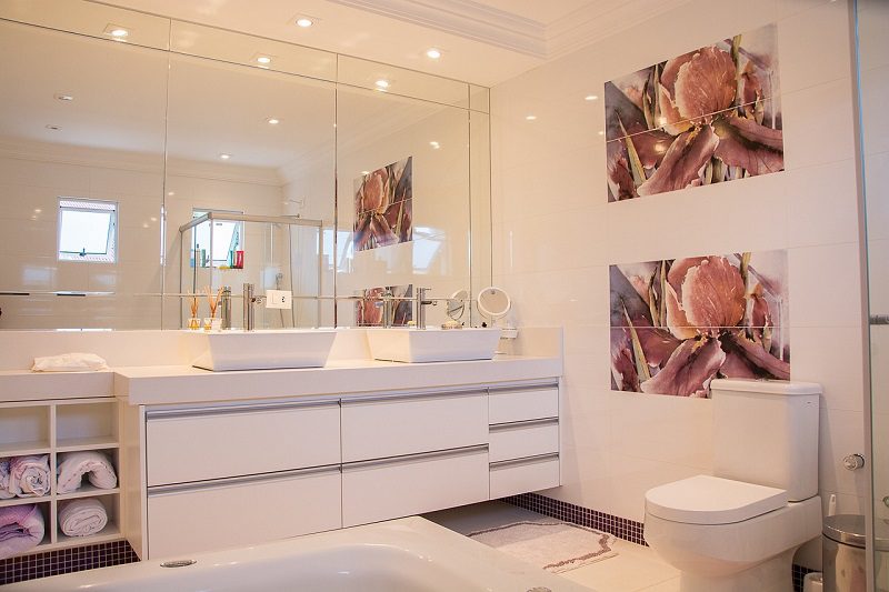 A bathroom with white walls and a large mirror.