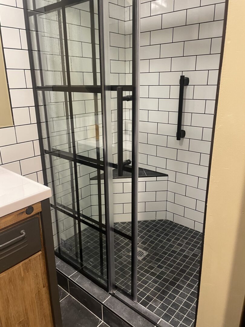 A bathroom with a glass shower door and tiled walls.