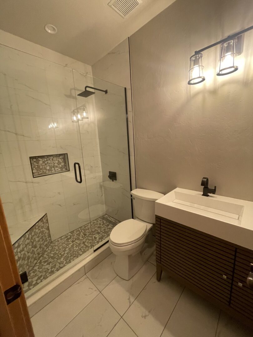 A bathroom with a toilet, sink and shower.